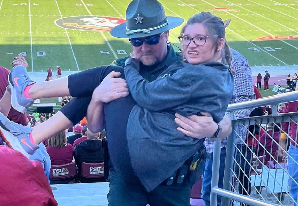 Se hace viral la foto de un policía de Florida cargando a una niña que se esfuerza por subir las escaleras de un estadio